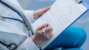 Top view of medical documentation being filled by female doctor at doctor's office